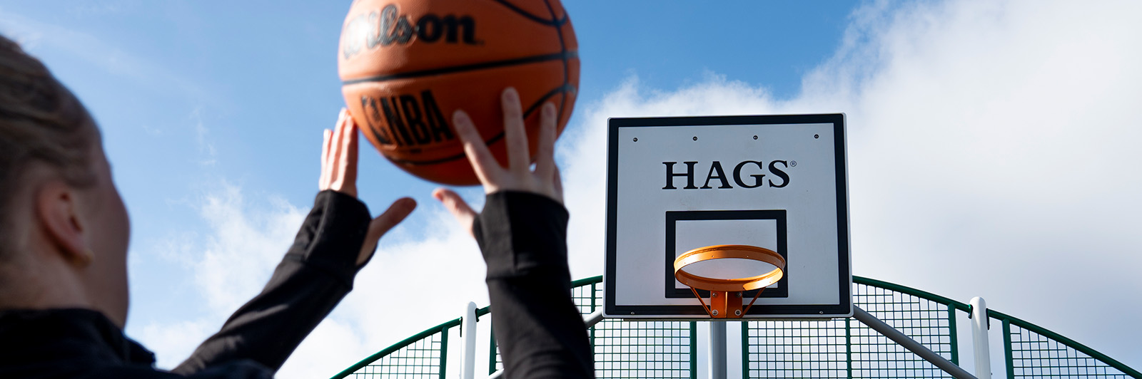 Girl throwing a basketball in to a baketball hoop.